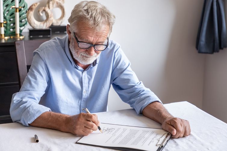 Senior old man elderly examining and signing last will and testa